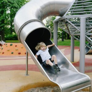 Child enjoying a slide at a modern playground, showcasing fun and laughter.